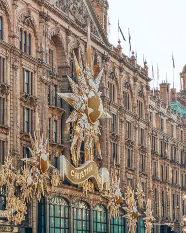 Christmass Magic at Harrods in London Historisch gebouw met gouden zonneschijnversieringen en vlaggen.